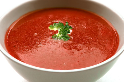 Heiße Tomatensuppe in einer Schüssel mit frischen Kräutern angerichtet